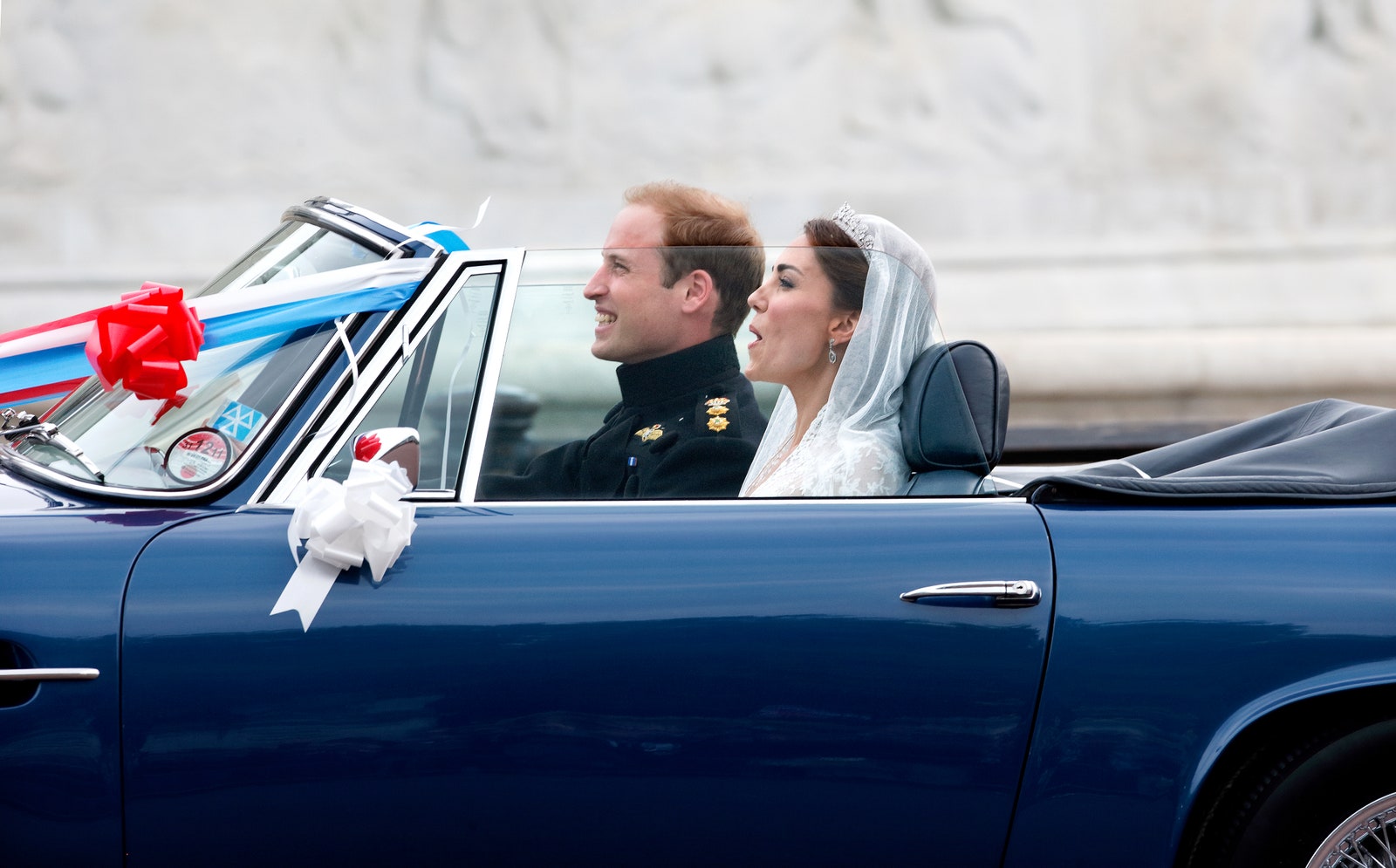 De hertog en hertogin van Cambridge verlaten Buckingham Palace in de Aston Martin DB6 Volante uit 1969 van prins Charles, versierd met vlaggen, linten en ballonnen