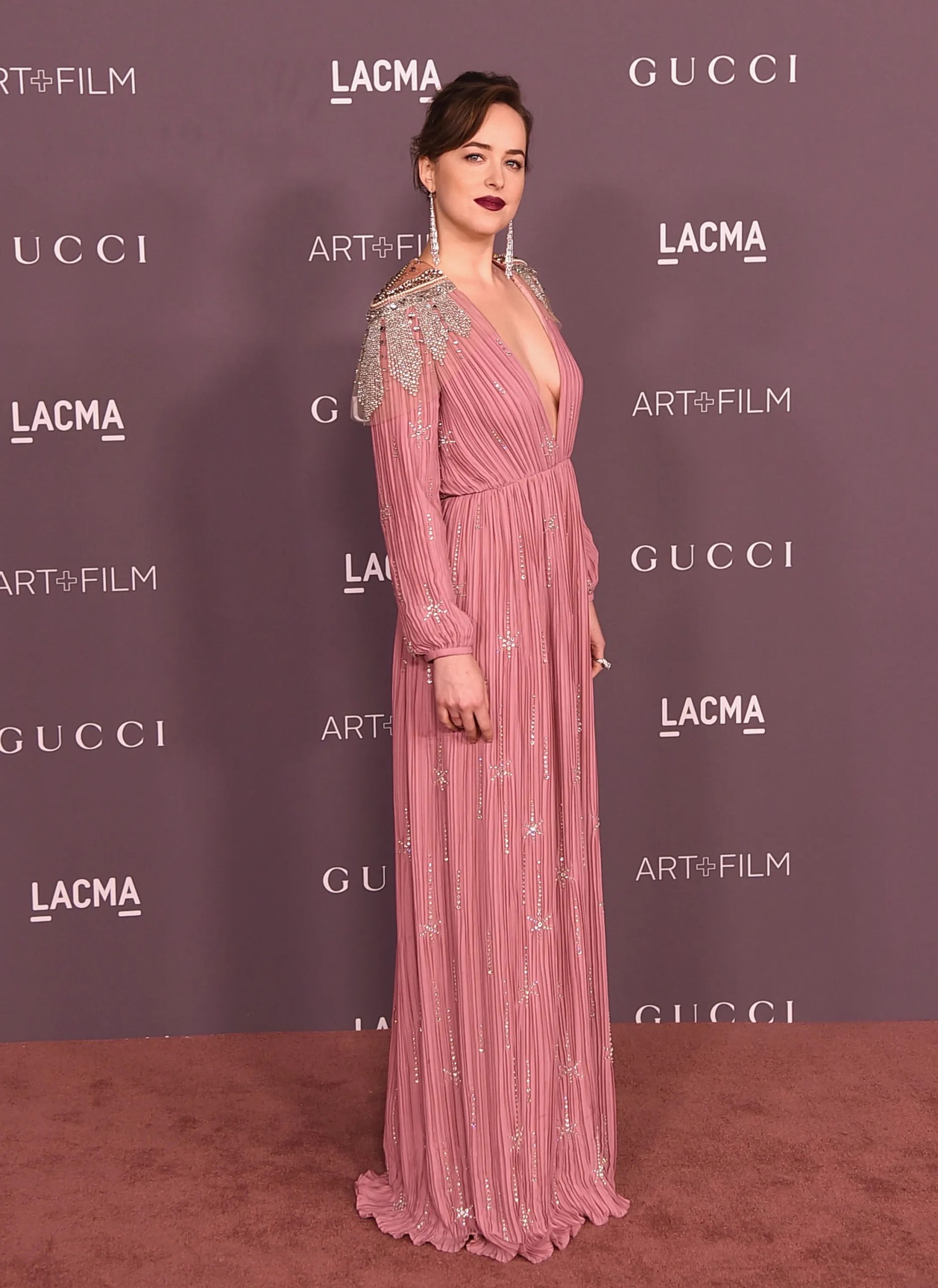 Als Dakota roze doet, is het verleidelijk, niet zoet. Het robe-achtige silhouet, de kristallen details en de wijnrode lippen maken de look tijdens het LACMA Gala in 2017 volwassen in plaats van meisjesachtig.