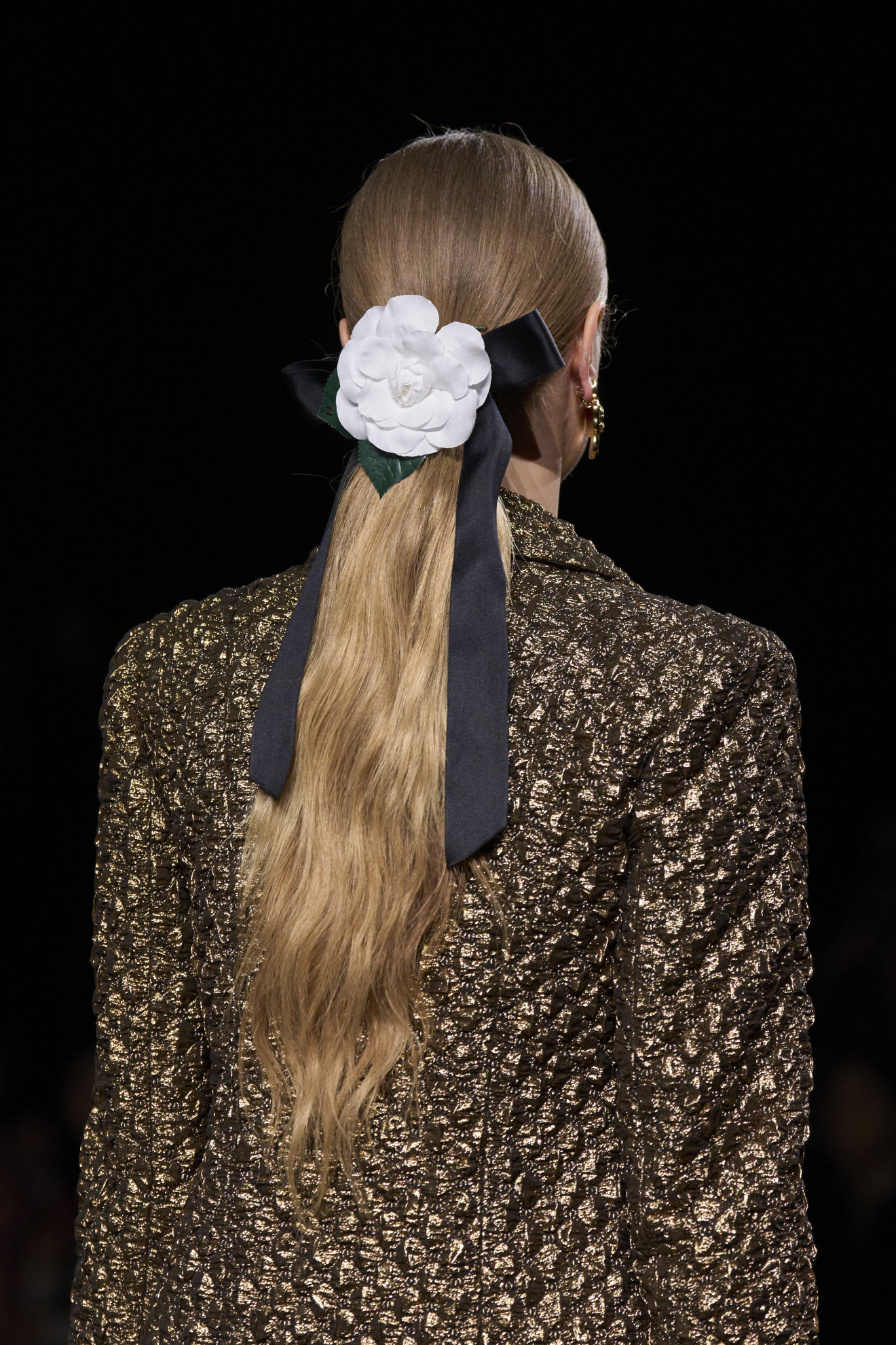 Een grote camellia in het haar van een model bij de Chanel-show