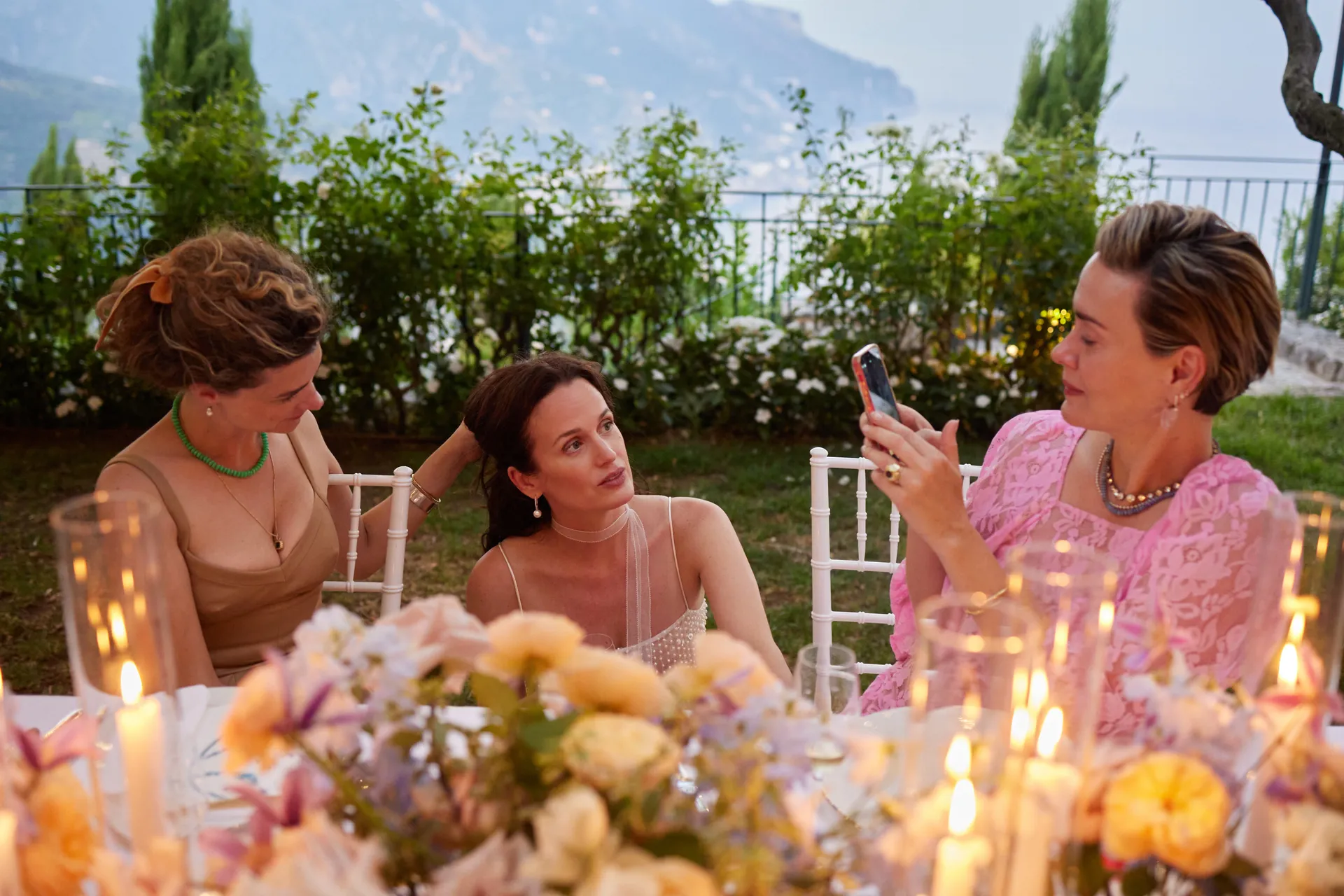 De gasten zitten aan tafel en Elizabeth zit gehurkt tussen de stoelen 