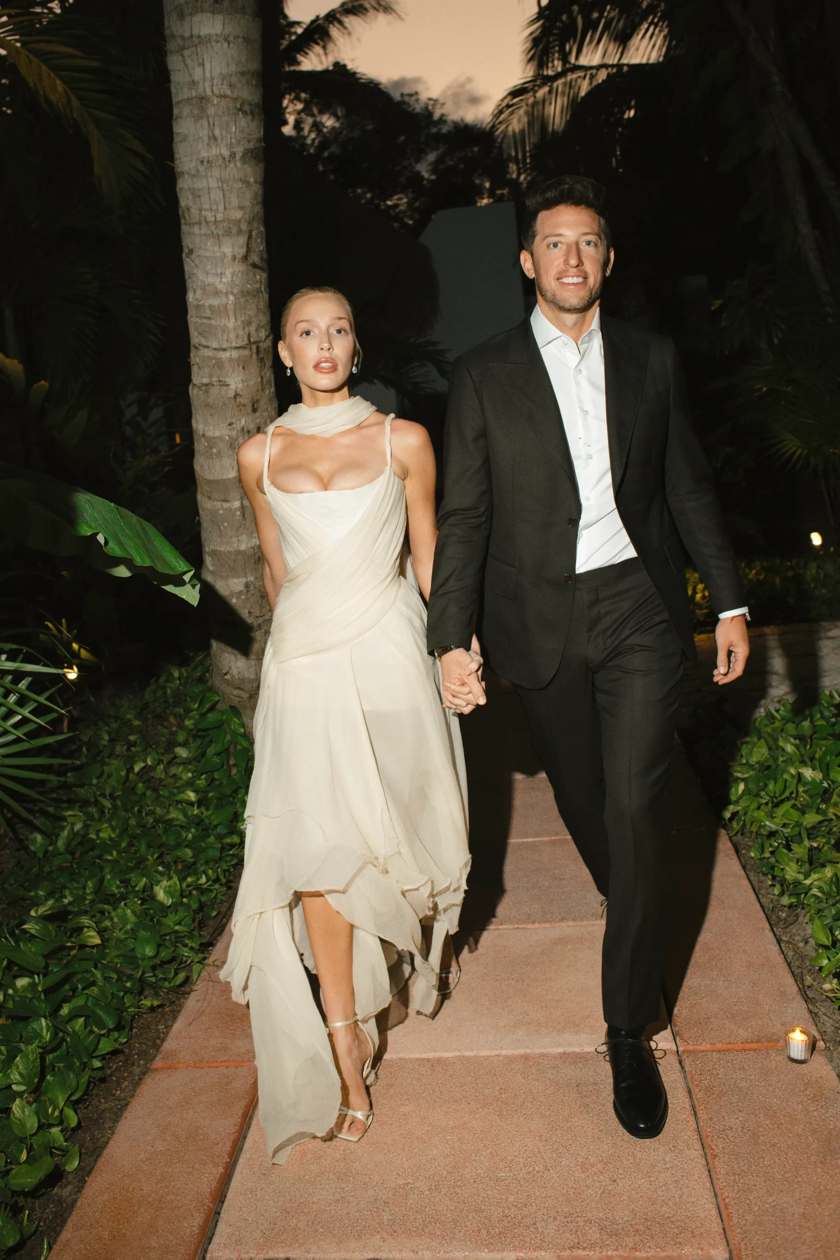 Alex draagt een zijden chiffon korsetjurk uit de lente/zomer 2003 'Irene'-collectie van Alexander McQueen, gecombineerd met Jimmy Choo Metz-sandalen.