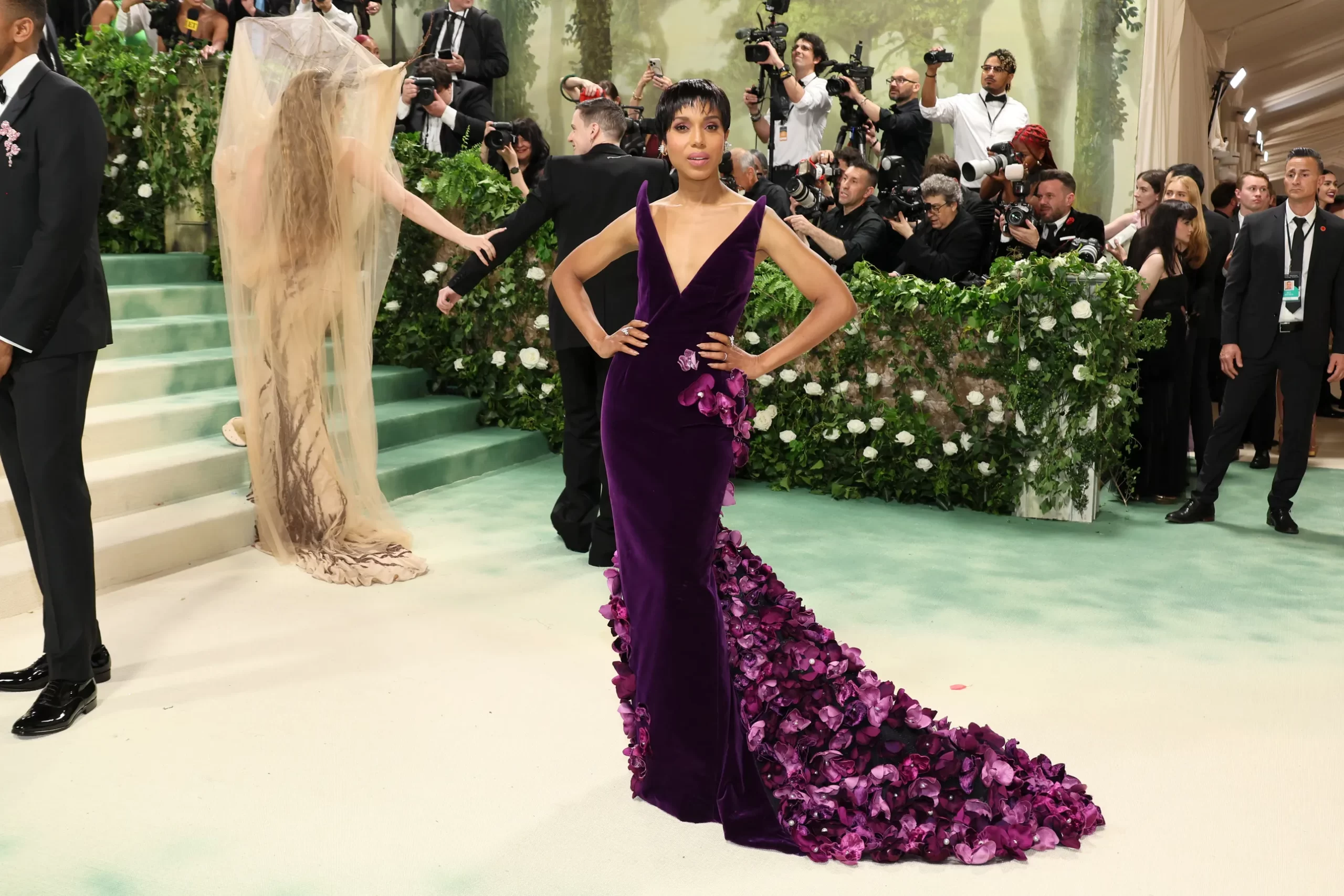 Kerry Washington in een donkerpaarse jurk met bloemen op de sleep
