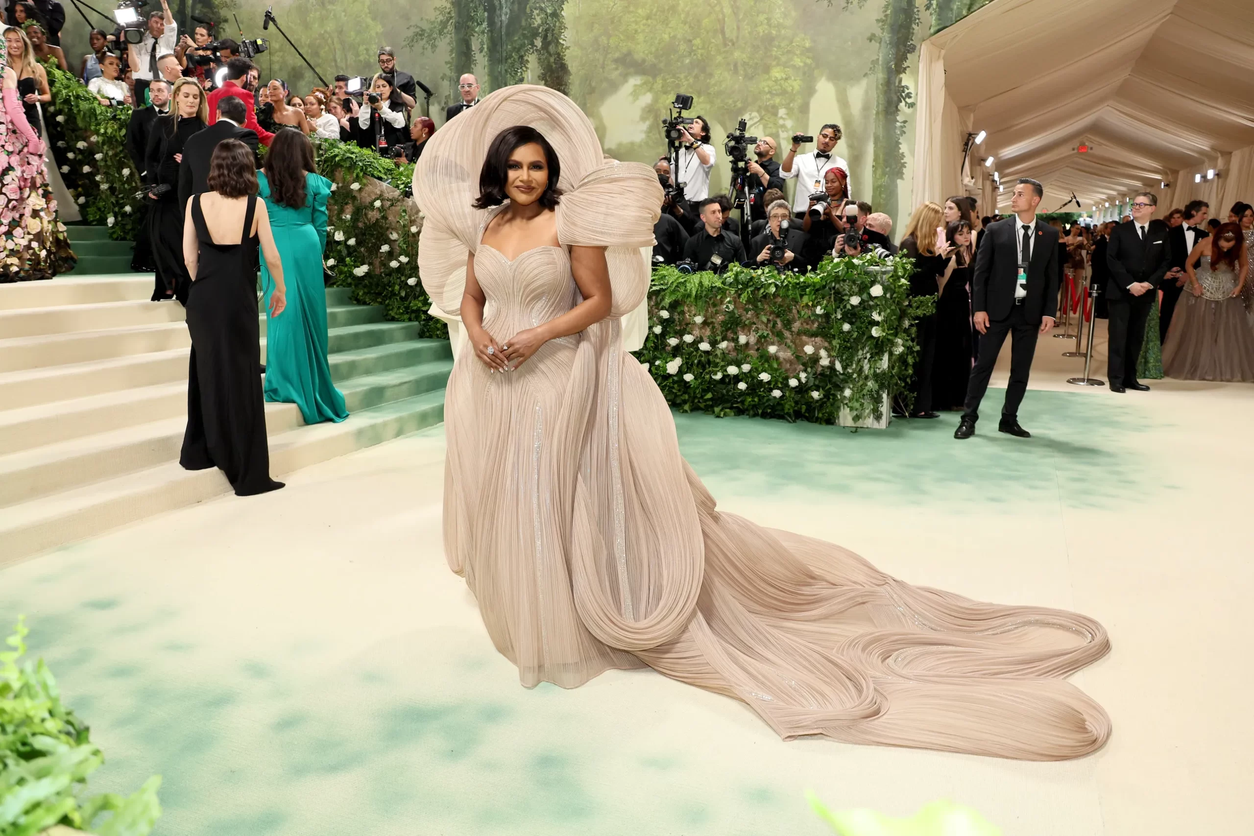 Mindy Kaling in een nude jurk met dramatische vormen om het hoofd