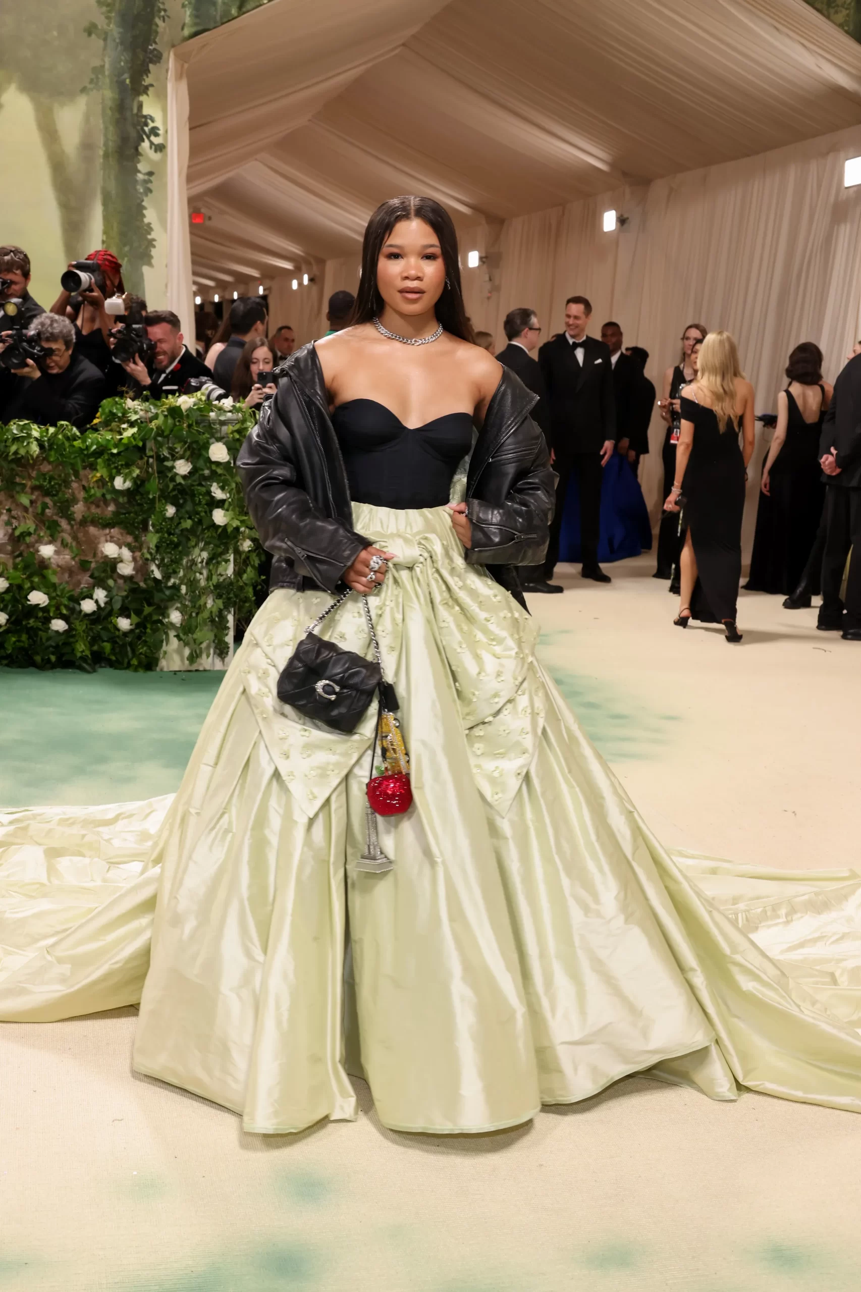 Storm Reid in een baljurk met zwarte bustier, lichtgroene rok en een leren jas