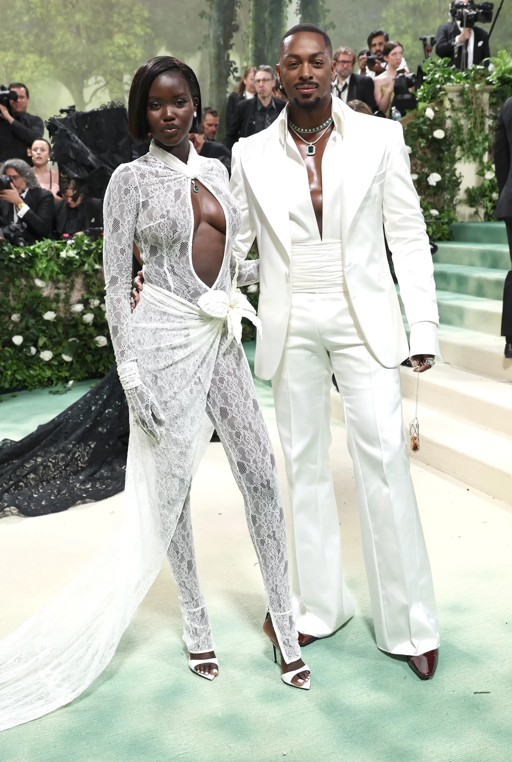 Aduth Akech in een wit kanten ensemble en LaQuan Smith in een wit pak