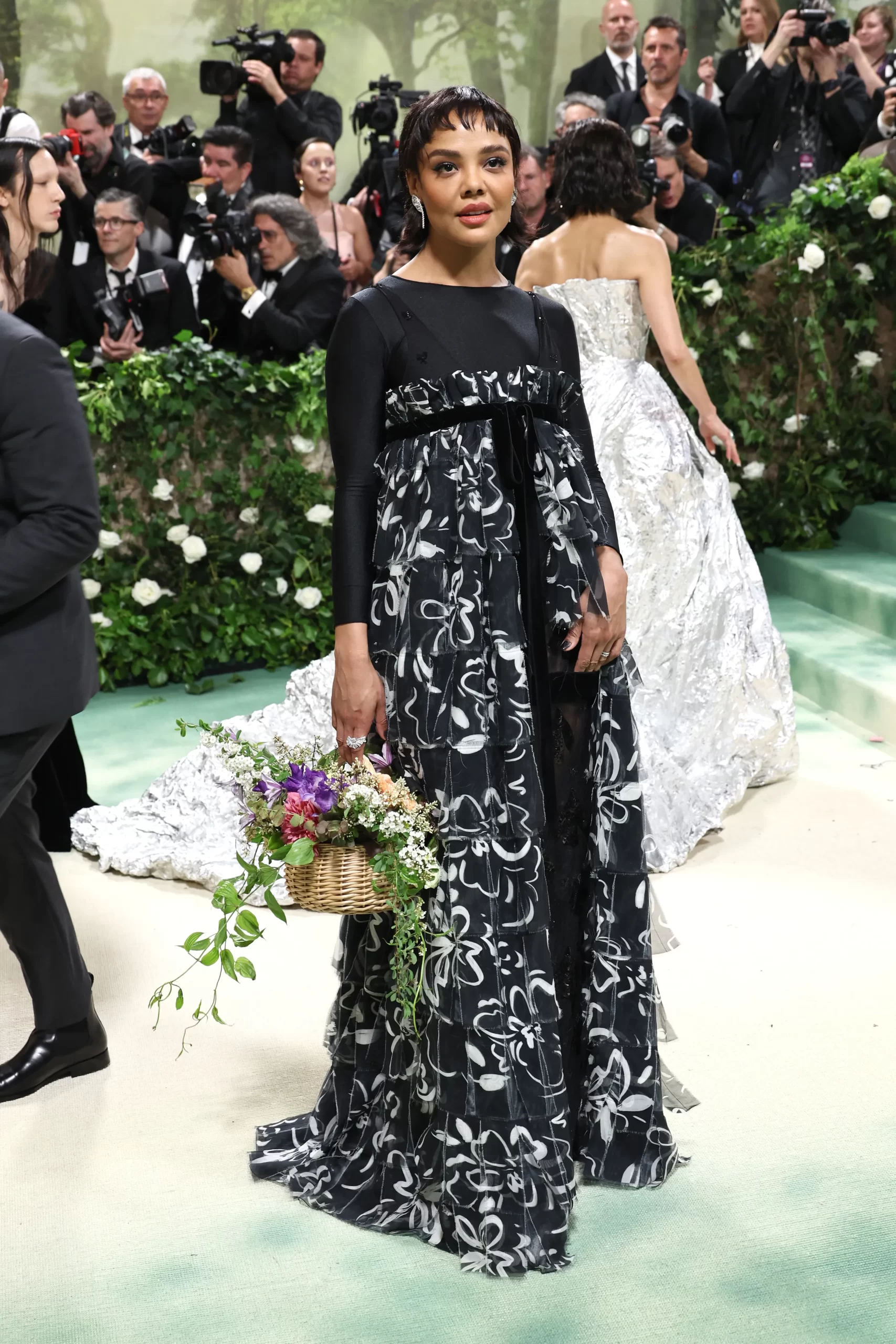 Tessa Thompson in een zwart-witte bloemenjurk met bloemenmand
