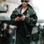Een streetstyler draagt een oversized zwarte leren jas