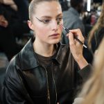 Model krijgt een touch up backstage met make-upkwasten.