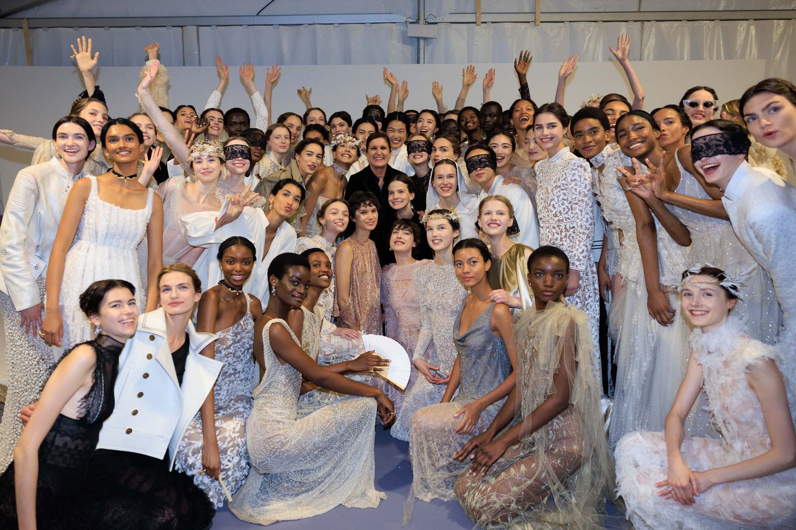 Maria Grazia Chiuri poses with models backstage at the Dior resort 2026 show.