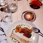 Een eettafel met gerecht en glas wijn.