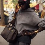 Een vrouw met een koptelefoon op straat tijdens PFW