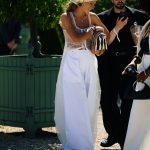 Een showgast draagt een wijde witte palazzobroek