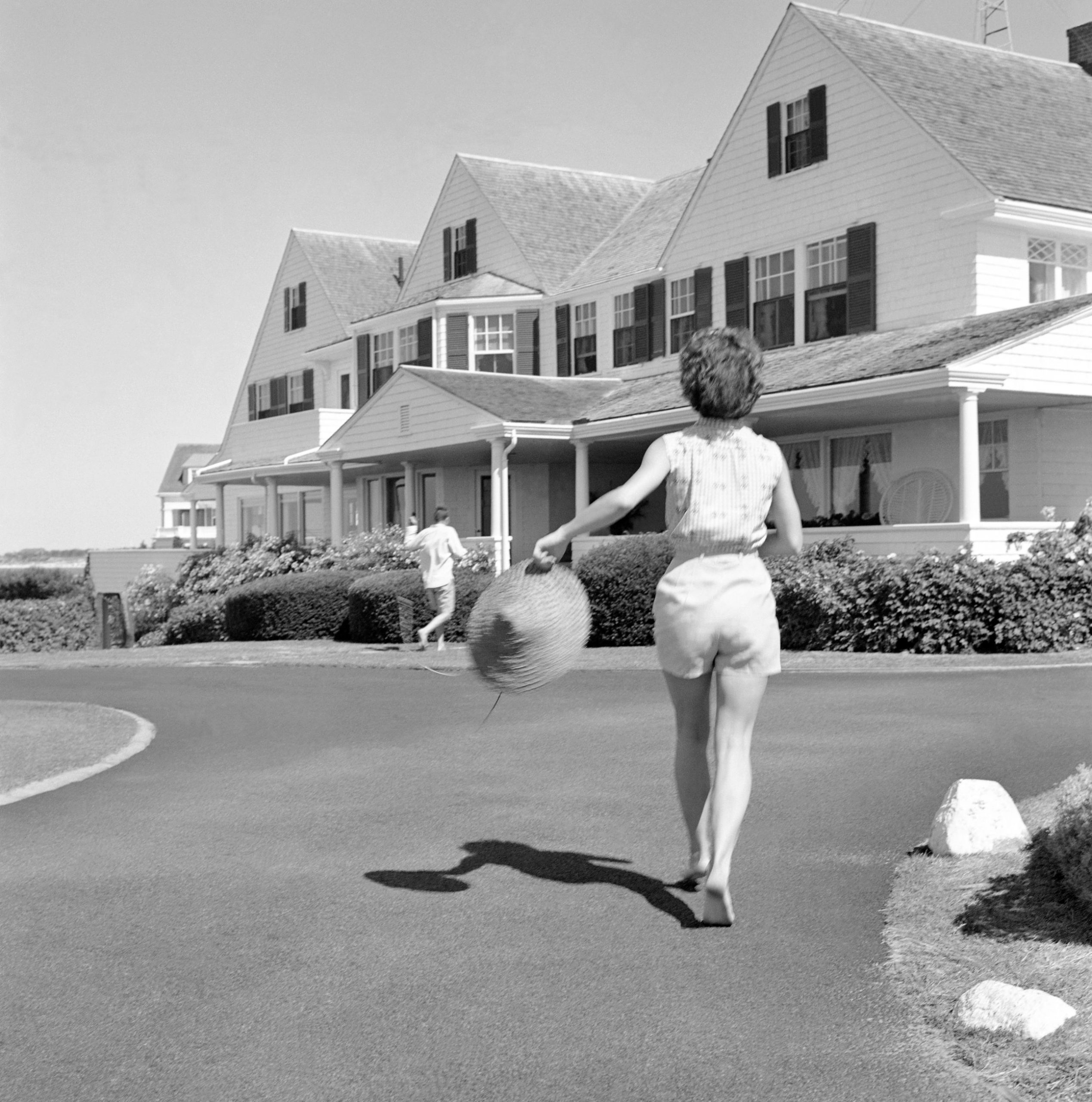 John F. Kennedy en Jackie Kennedy rennen richting het huis tijdens hun vakantie op het Kennedy-compound.