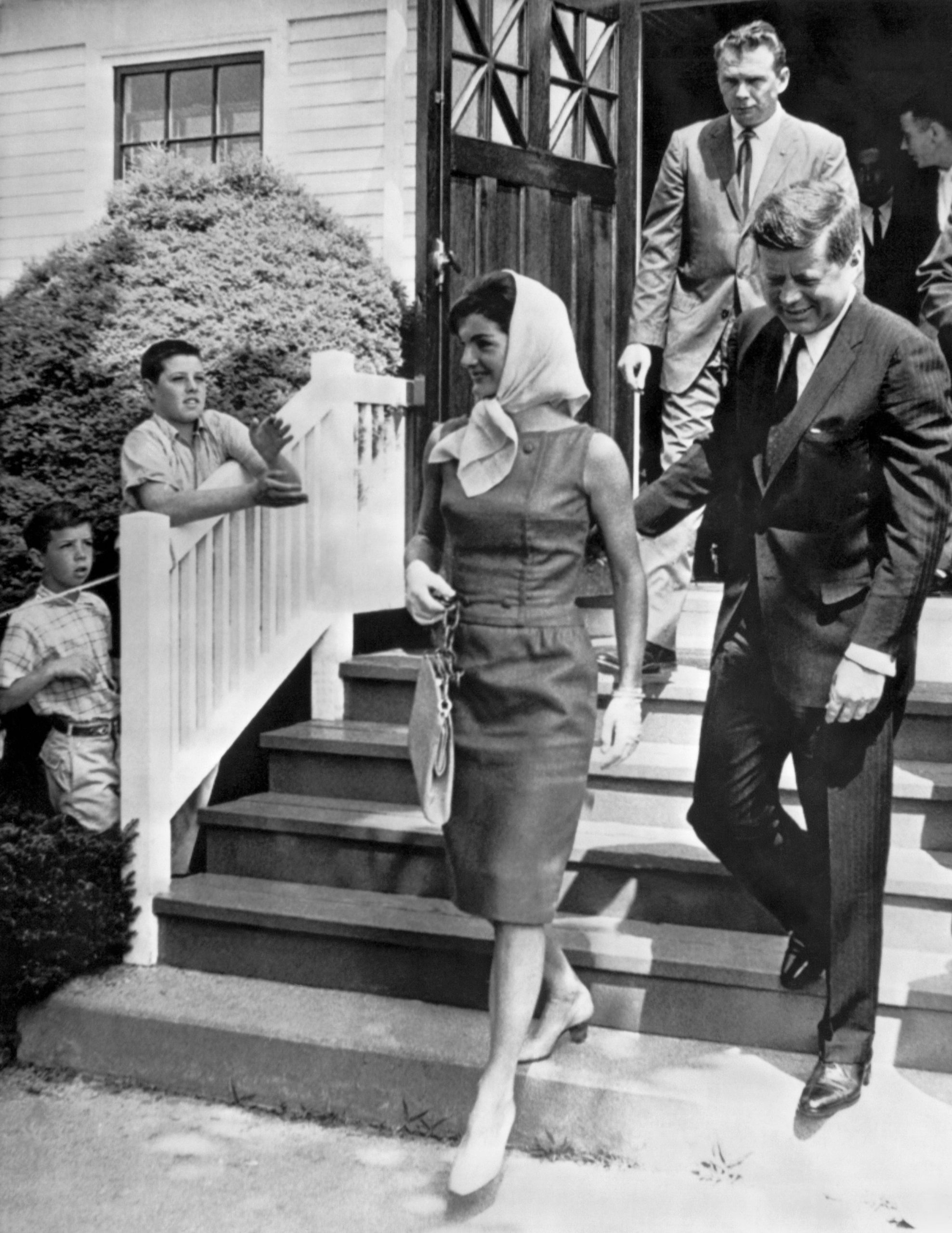De president en first lady na het bijwonen van een mis in Hyannis, Massachusetts, op 2 juli 1961. Jacqueline draagt een groene linnen jurk en een witte hoofddoek.