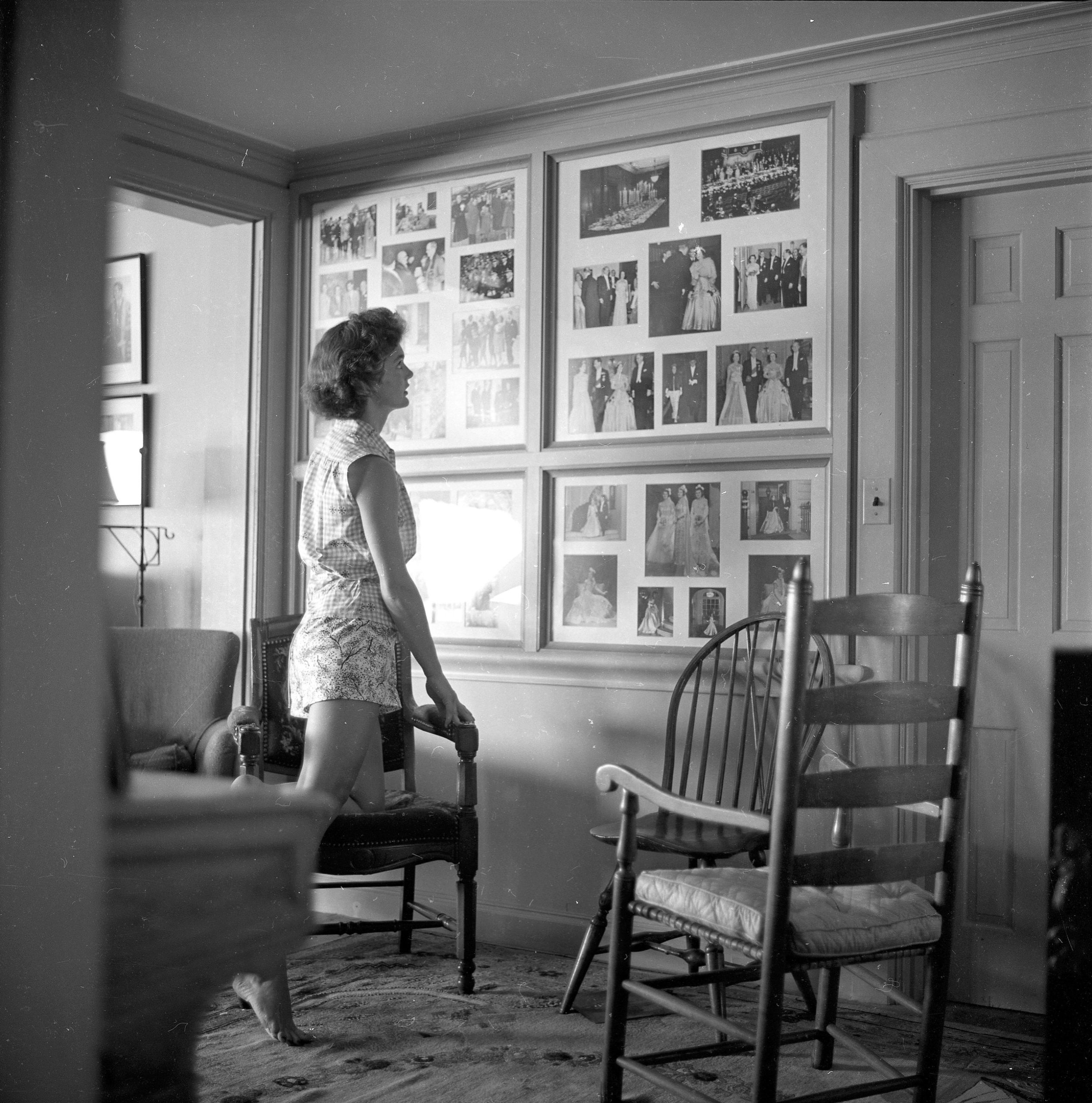 Jackie Kennedy bekijkt familiefoto’s in het huis in Hyannis Port.