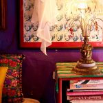 Een kleurrijke slaapkamer met een nachtkastje vol met boeken