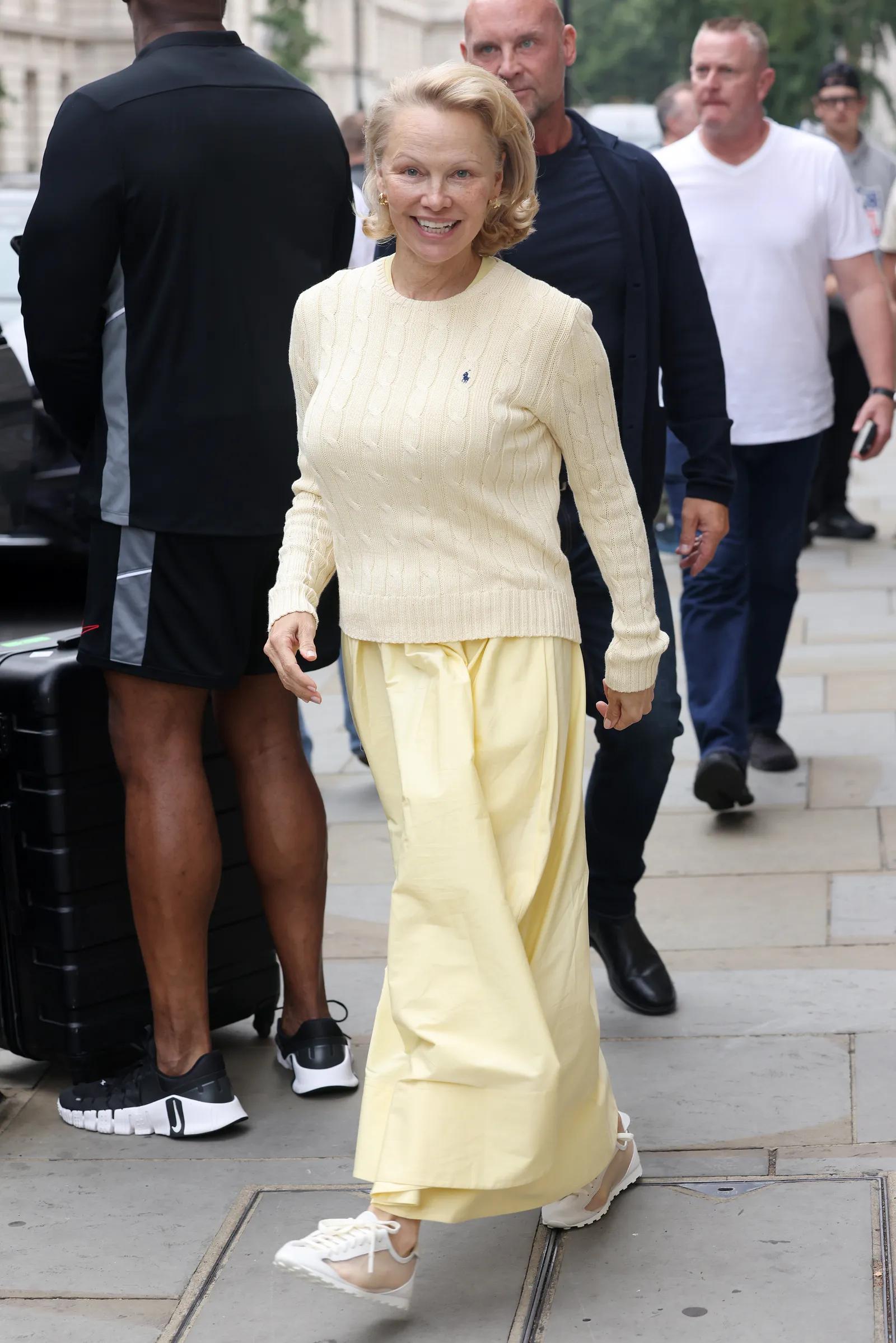Pamela Anderson draagt een botergele look en doorschijnende sneakers van Jacquemus