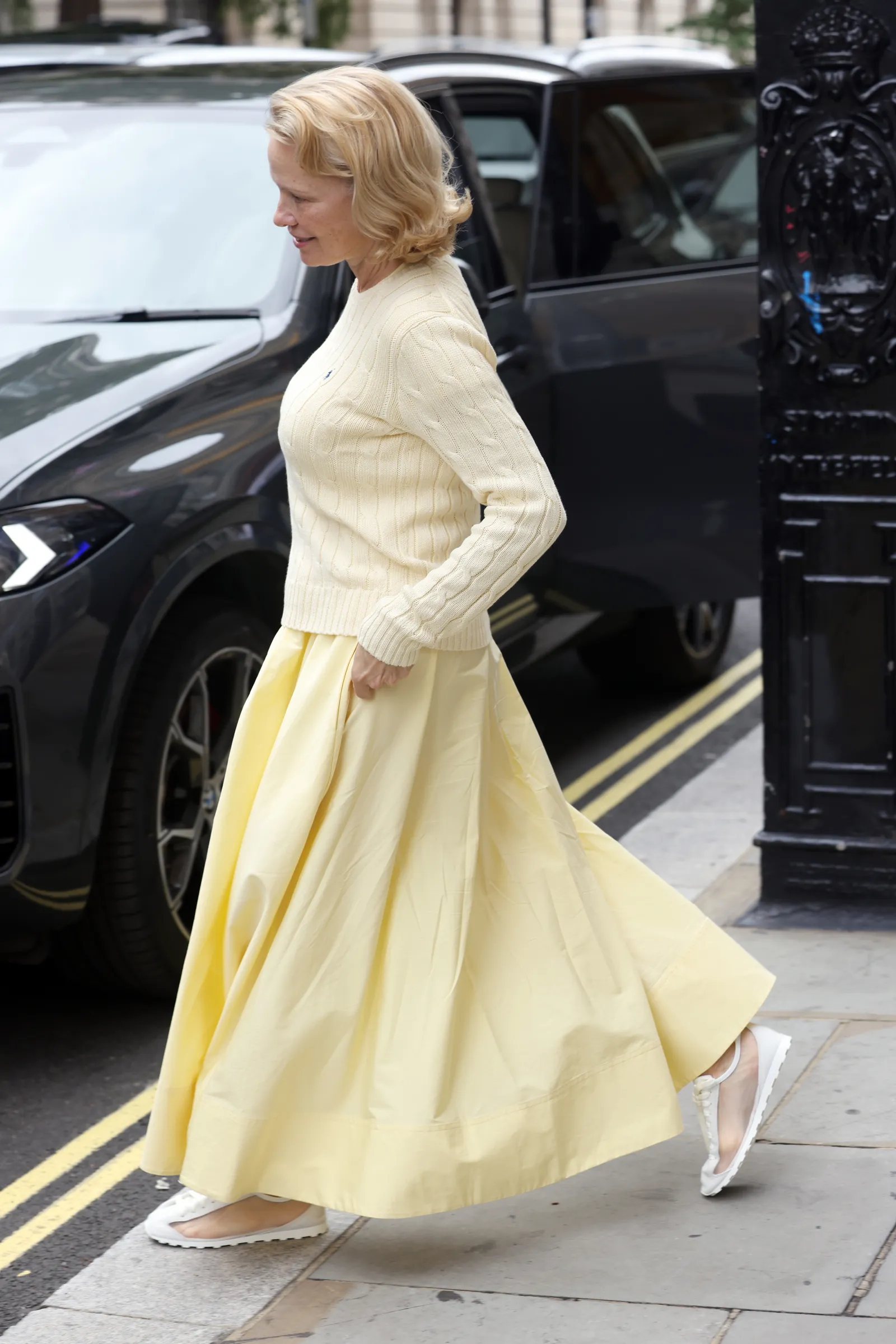 Pamela Anderson draagt een botergele look en doorschijnende sneakers van Jacquemus
