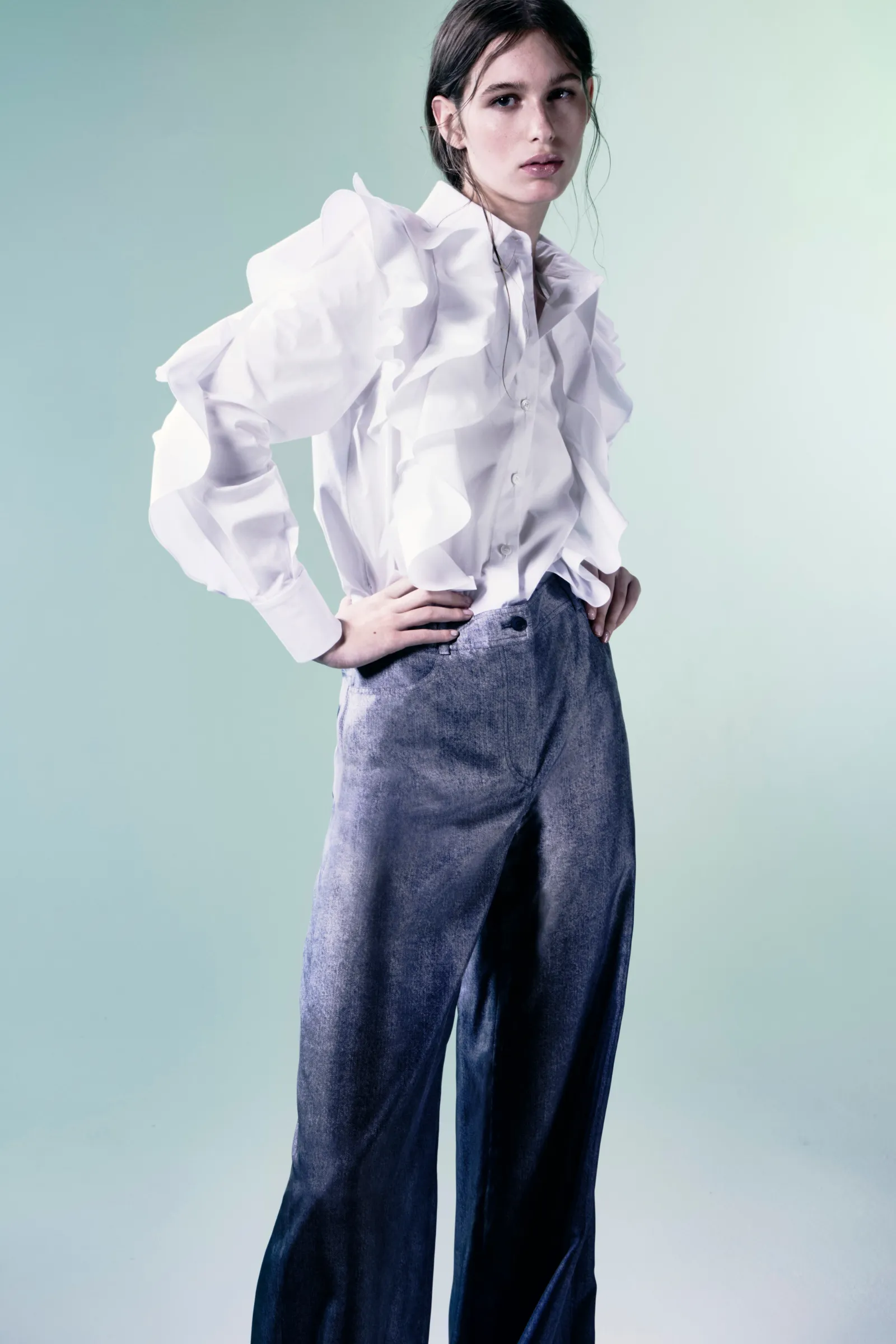 Model met witte blouse met rushes en jeans