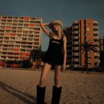 Een model staat op een strand, gefotografeerd door Kate Bellm voor Vogue's mei 2024-nummer