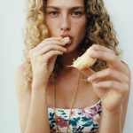 Een model eet een stuk fruit