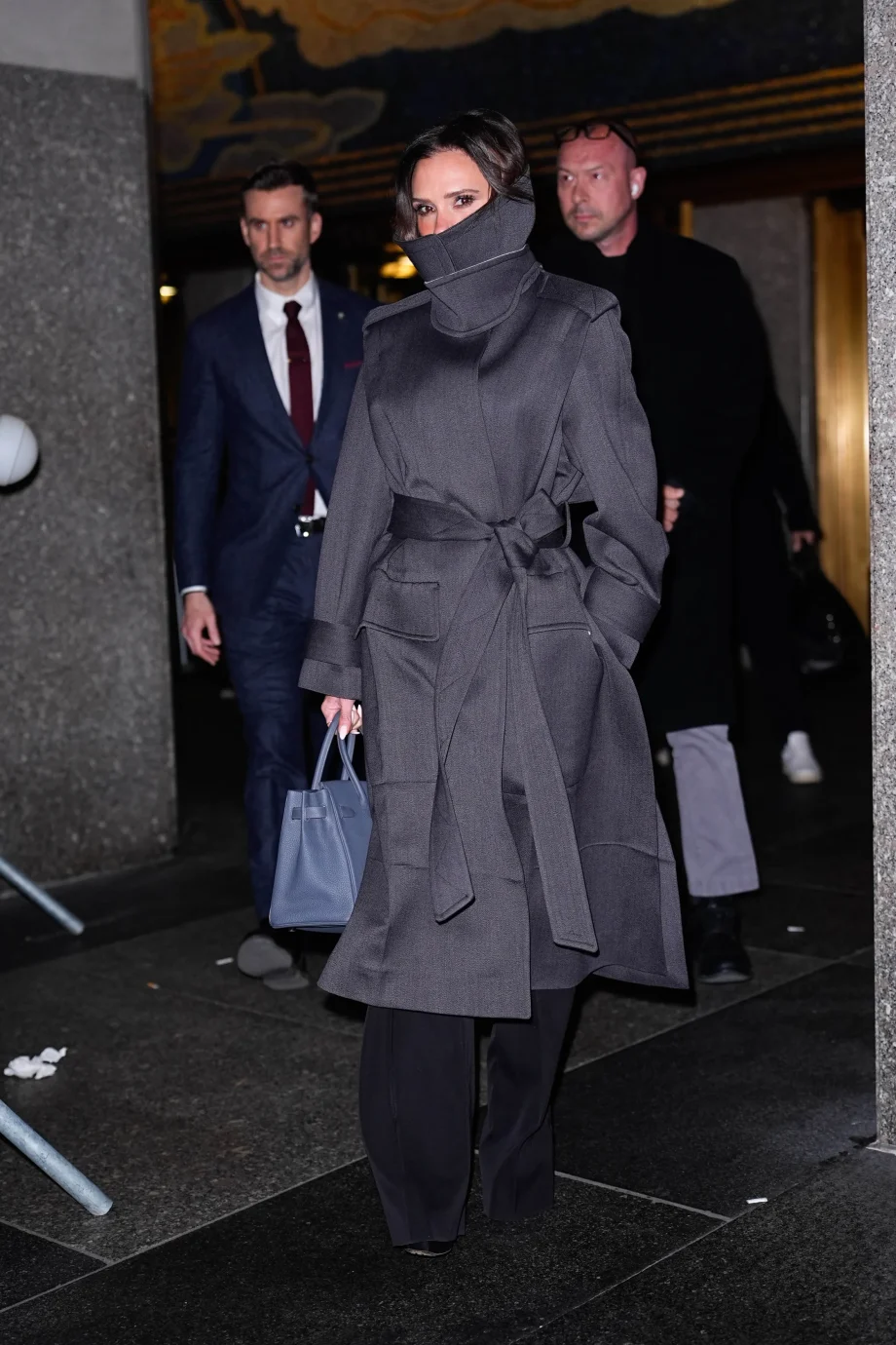 victoria-beckham-verhult-haar-glimlach-zoals-alleen-zij-dat-kan-in-een-stijlvolle-trenchcoat-met-hoge-kraag-376379