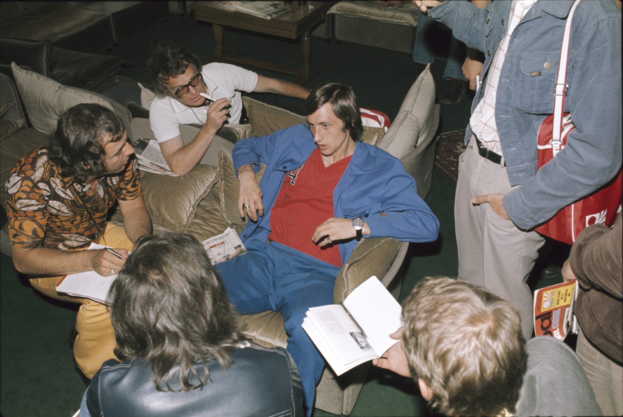 De voetballer omringd door journalisten.