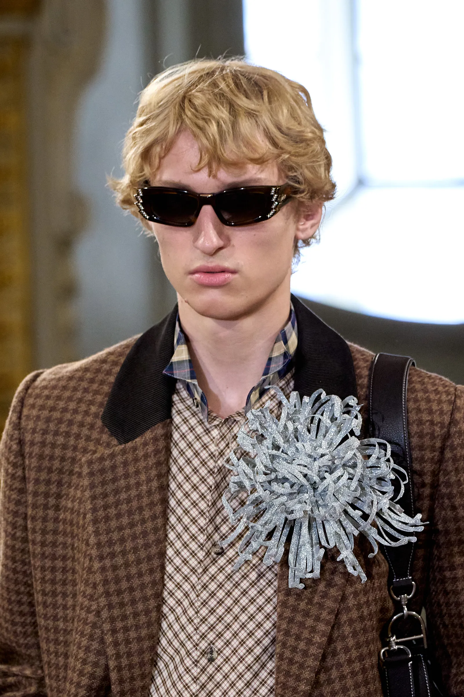 Een man met een broche op de catwalk