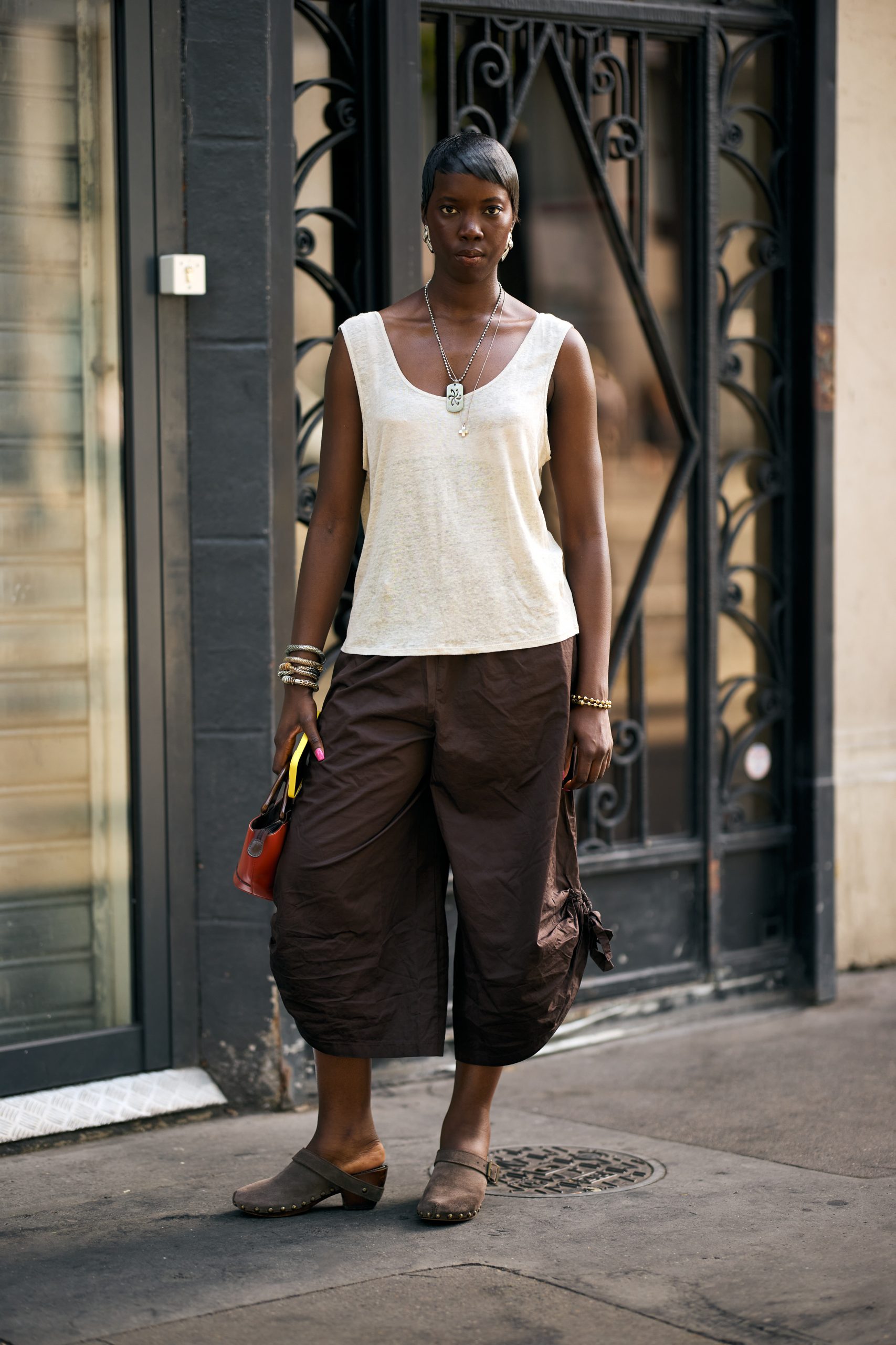 Model draagt lange broek met clogs.